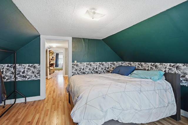 bedroom featuring wood finished floors, a textured ceiling, and vaulted ceiling