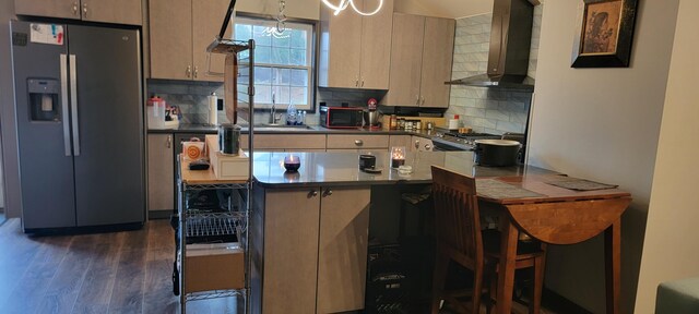 kitchen featuring appliances with stainless steel finishes, wall chimney range hood, a sink, a peninsula, and backsplash