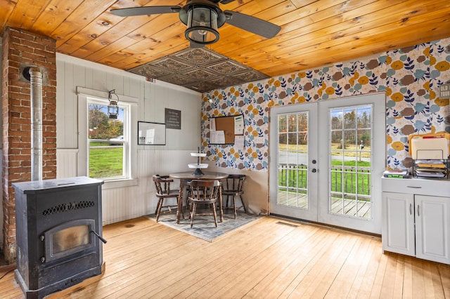 dining space featuring french doors, a wood stove, wallpapered walls, wooden ceiling, and ceiling fan