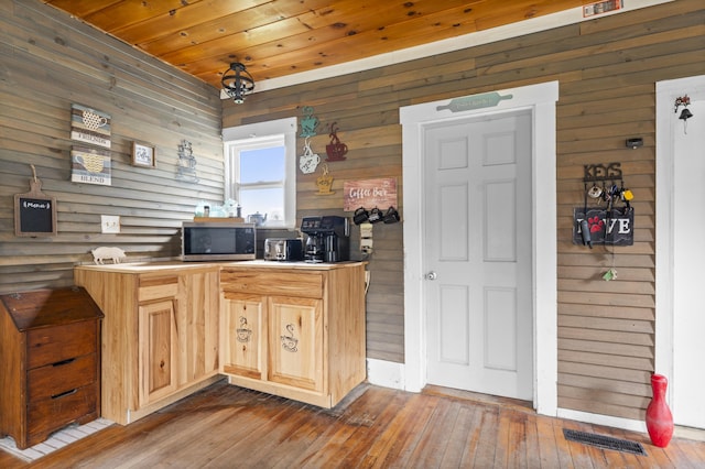 kitchen featuring stainless steel microwave, wooden ceiling, wood walls, wood-type flooring, and light brown cabinetry