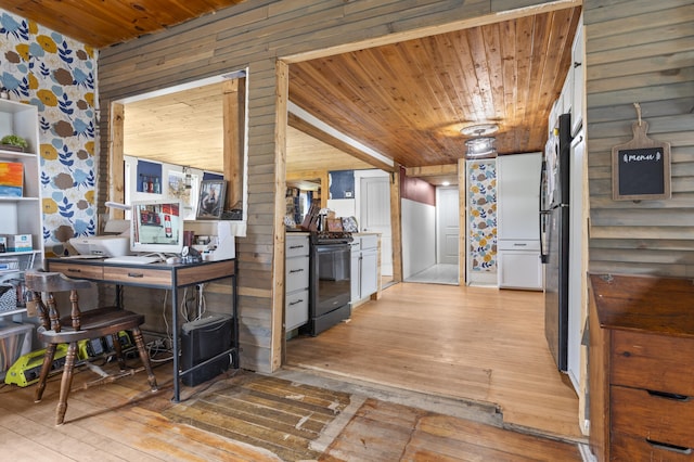 kitchen with black appliances, light wood-style flooring, wooden ceiling, a desk, and wood walls