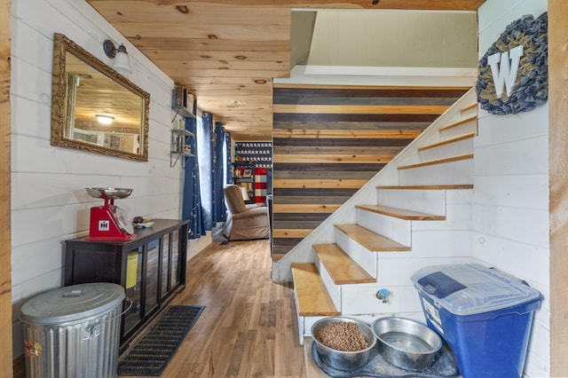 stairs featuring wood finished floors, wooden walls, and wooden ceiling