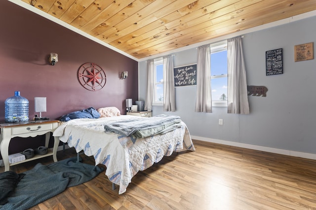 bedroom with wood ceiling, wood finished floors, baseboards, and ornamental molding