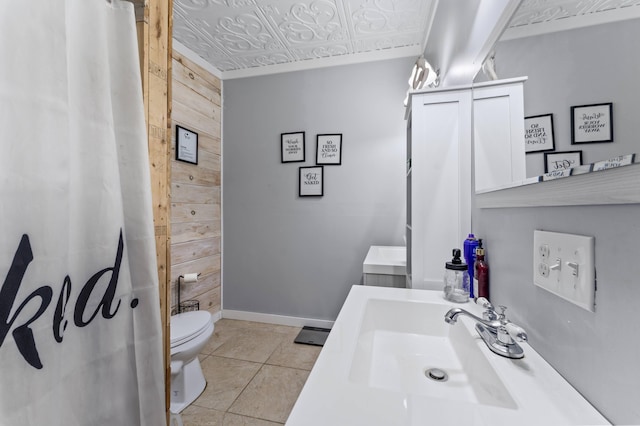 bathroom with wood walls, an ornate ceiling, toilet, baseboards, and vanity