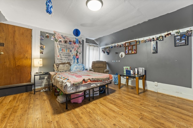 bedroom with wood finished floors and vaulted ceiling