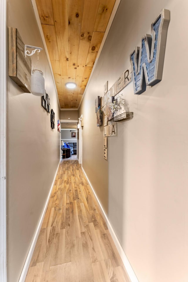 hallway with wood finished floors, wooden ceiling, and baseboards