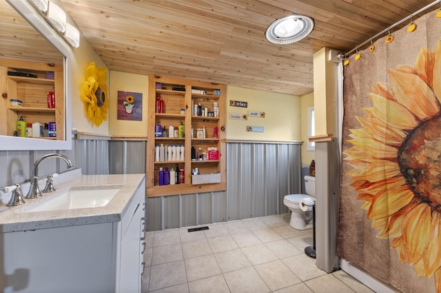 full bathroom featuring a wainscoted wall, tile patterned floors, wood ceiling, toilet, and vanity