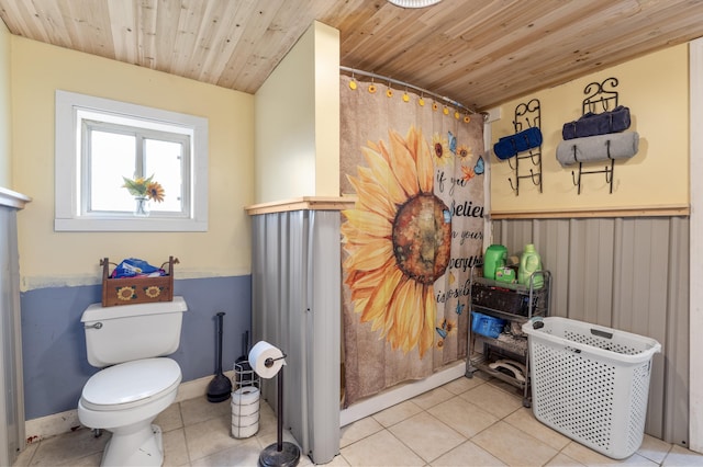 bathroom featuring wood ceiling, tile patterned flooring, toilet, a shower with shower curtain, and a wainscoted wall