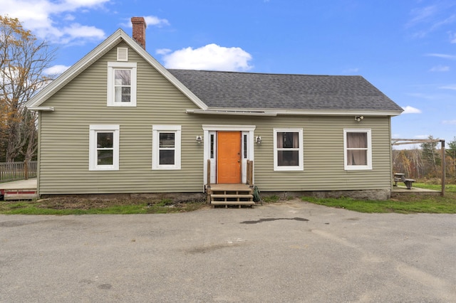 view of front of home with a chimney and a shingled roof