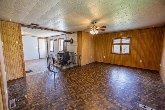 225 Todds Corner Rd, Saint Albans, ME 04971 - unfurnished living room with a wood stove, ceiling fan, wooden walls, and baseboards