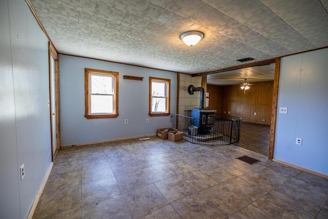 225 Todds Corner Rd, Saint Albans, ME 04971 - unfurnished living room with a wood stove, wood walls, ceiling fan, and baseboards