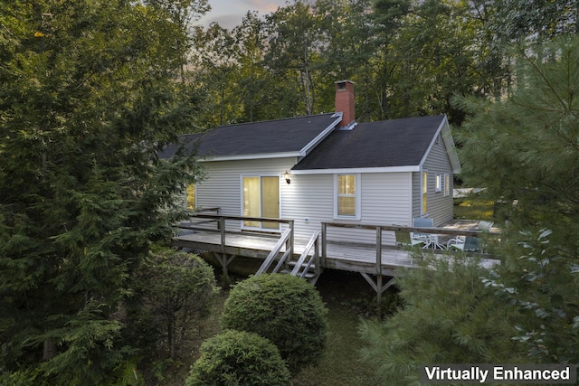 back of property with a chimney, a deck, and roof with shingles