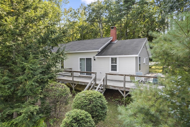 rear view of house with roof with shingles, a chimney, and a wooden deck