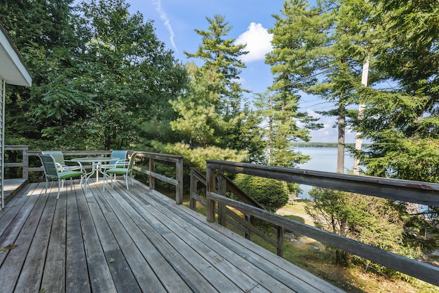 wooden terrace with a water view and outdoor dining space
