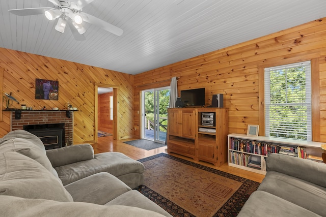 living area with wood finished floors, a ceiling fan, wooden walls, and a fireplace