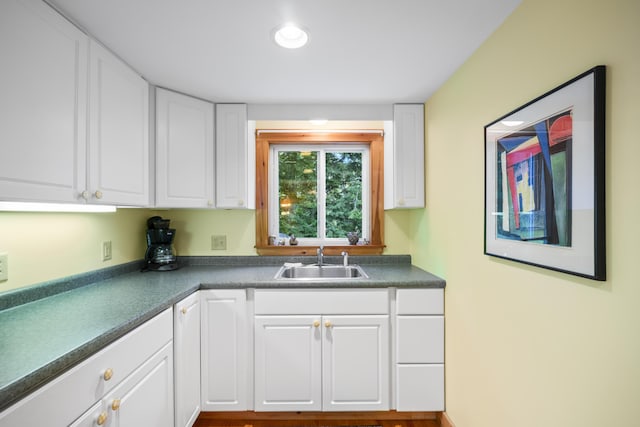 kitchen featuring a sink, dark countertops, and white cabinets