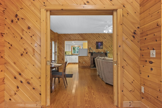 corridor featuring light wood-style flooring and wood walls