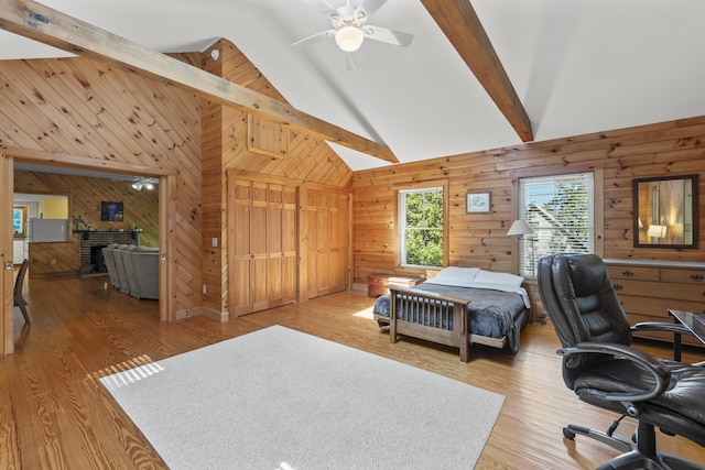 bedroom with wooden walls, beamed ceiling, wood finished floors, a desk, and high vaulted ceiling
