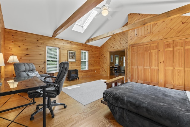 bedroom featuring beamed ceiling, a skylight, wooden walls, wood finished floors, and high vaulted ceiling