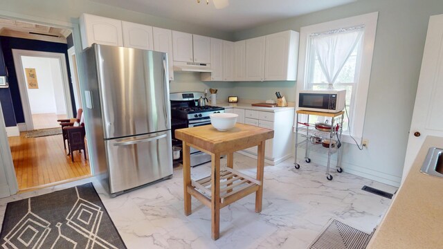 21 Fern St, Bangor, ME 04401 - kitchen featuring stainless steel appliances, under cabinet range hood, light marble finish floors, and white cabinetry