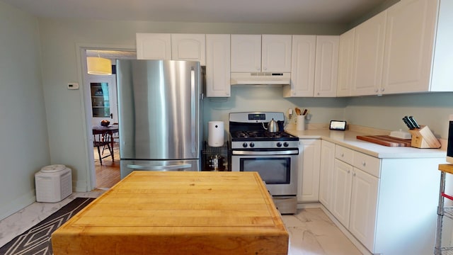 21 Fern St, Bangor, ME 04401 - kitchen featuring appliances with stainless steel finishes, under cabinet range hood, light marble finish flooring, and white cabinetry