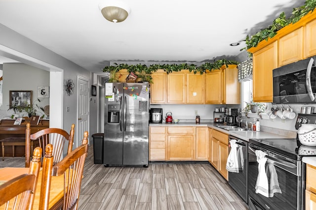 kitchen featuring appliances with stainless steel finishes, light brown cabinetry, a sink, and light countertops