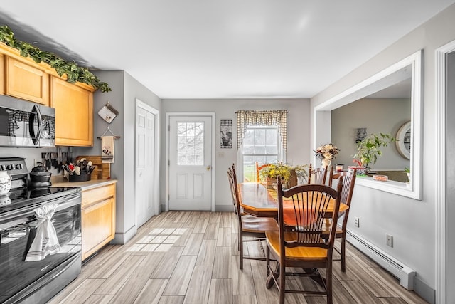 kitchen featuring appliances with stainless steel finishes, light brown cabinetry, baseboard heating, and wood finish floors