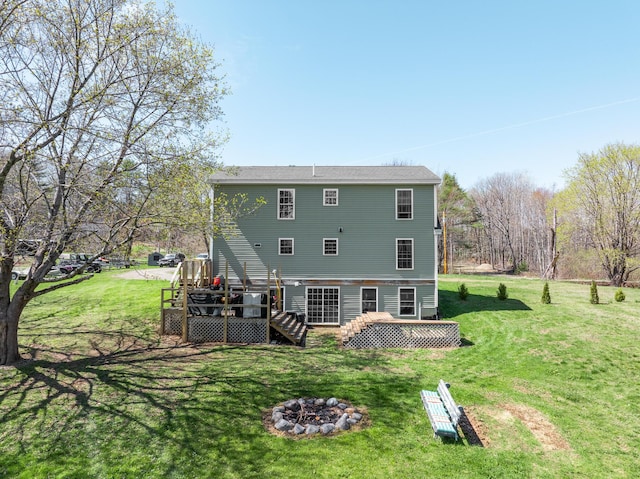 back of property featuring a deck, an outdoor fire pit, a lawn, and stairs
