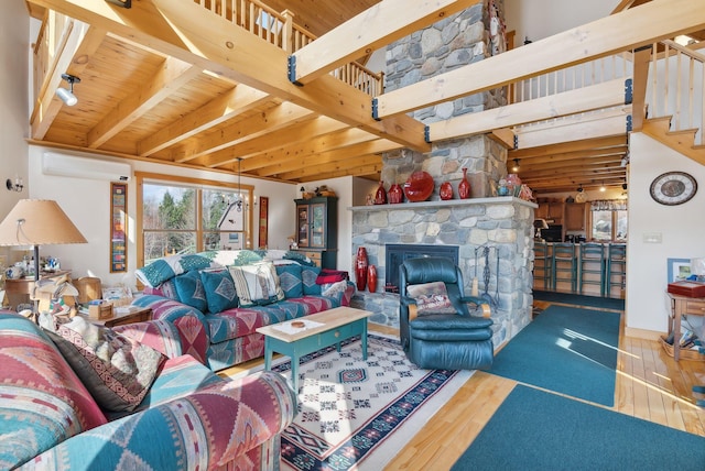 237 River Rd, Avon, ME 04966 - living room featuring a wall unit AC, wood finished floors, beam ceiling, stairs, and a stone fireplace