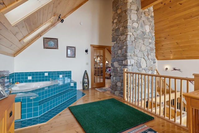 237 River Rd, Avon, ME 04966 - bathroom with wood ceiling, wood finished floors, high vaulted ceiling, a garden tub, and a skylight