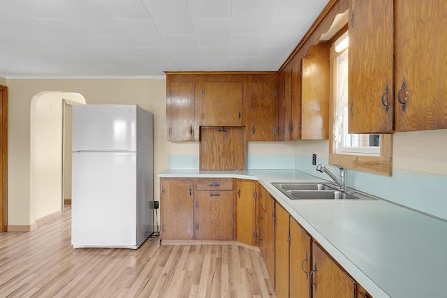 237 River Rd, Avon, ME 04966 - kitchen with freestanding refrigerator, a sink, light countertops, brown cabinetry, and light wood-style floors