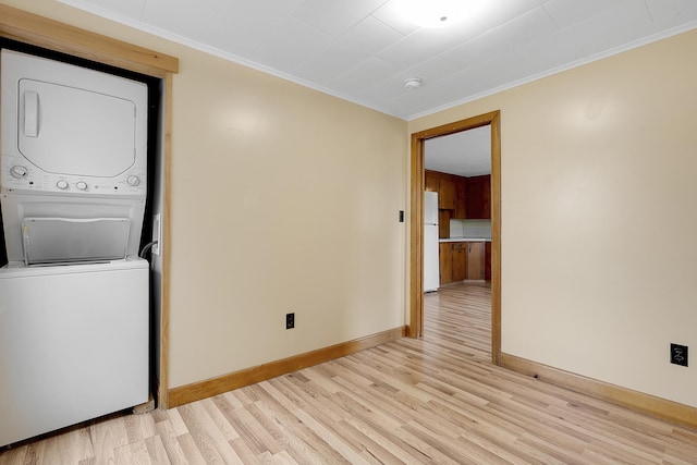 237 River Rd, Avon, ME 04966 - unfurnished room with stacked washing machine and dryer, light wood-style floors, baseboards, crown molding, and a smoke detector