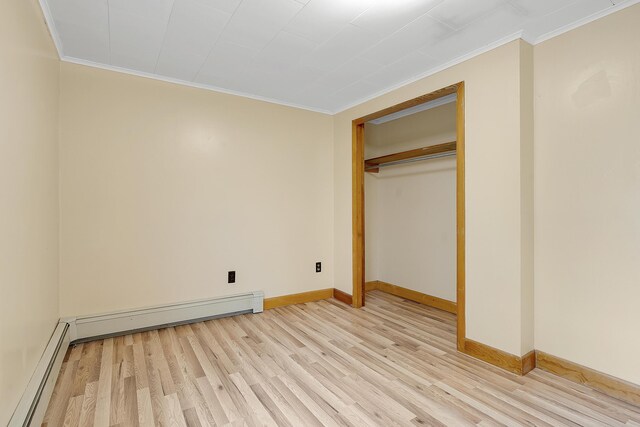 237 River Rd, Avon, ME 04966 - unfurnished bedroom with baseboard heating, ornamental molding, light wood-style flooring, baseboards, and a closet