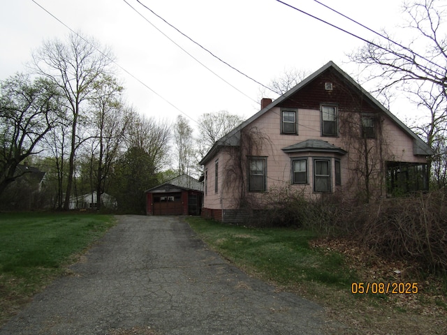 8 Water St, Milo, ME 04463 - view of front of home featuring an outdoor structure, asphalt driveway, a garage, a chimney, and a front lawn