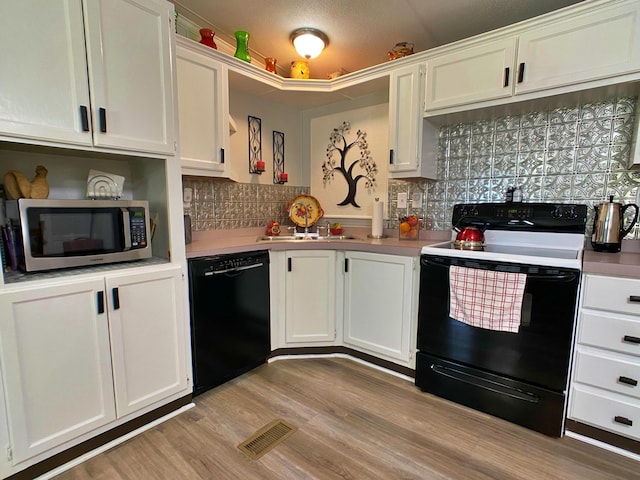 kitchen with black appliances, white cabinets, decorative backsplash, and light countertops