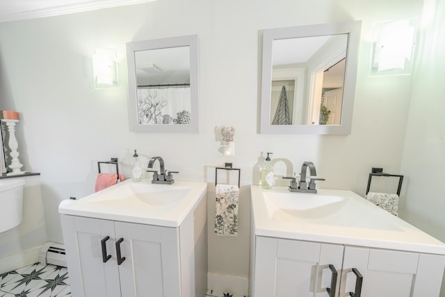 full bath featuring a baseboard radiator, two vanities, toilet, and baseboards
