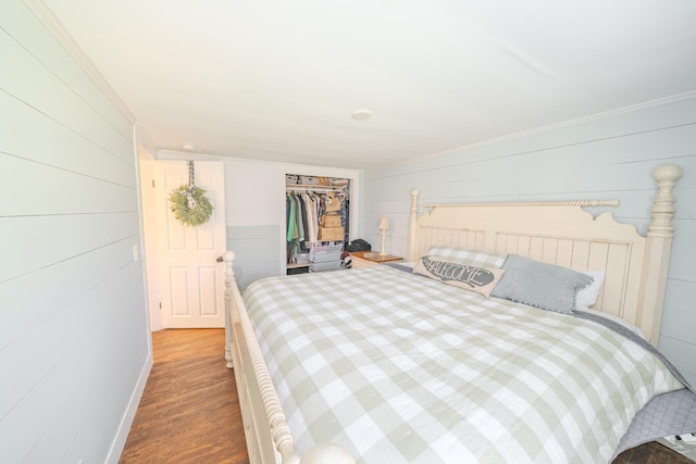bedroom with wood finished floors, ornamental molding, a closet, and wooden walls
