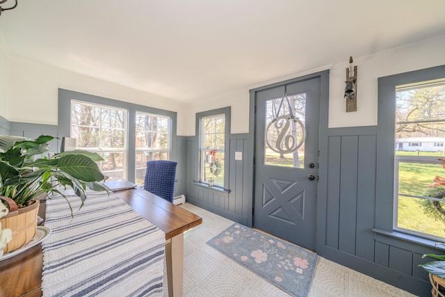 foyer with a decorative wall, wainscoting, plenty of natural light, and a baseboard heating unit
