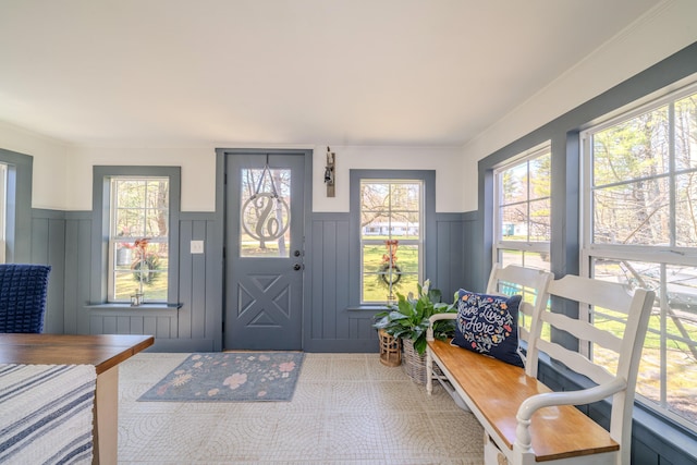 foyer entrance featuring a decorative wall and wainscoting