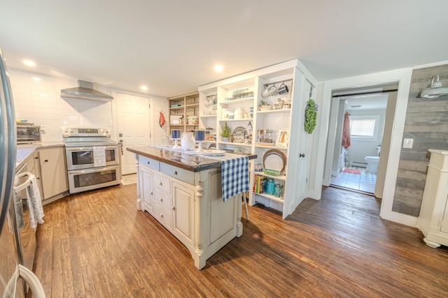 kitchen with double oven range, wall chimney range hood, dark wood-type flooring, open shelves, and a center island