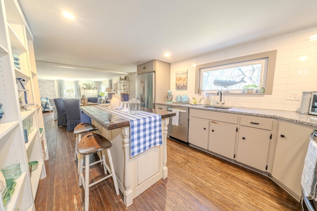 kitchen featuring appliances with stainless steel finishes, wood finished floors, tasteful backsplash, and open floor plan