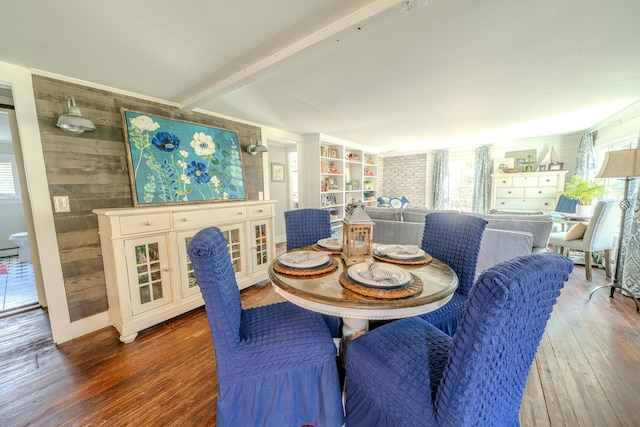 dining room with wood-type flooring, wood walls, and beamed ceiling