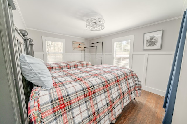 bedroom with wood-type flooring, ornamental molding, a wainscoted wall, and a decorative wall