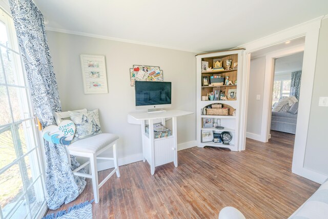 living area with wood finished floors, crown molding, and baseboards
