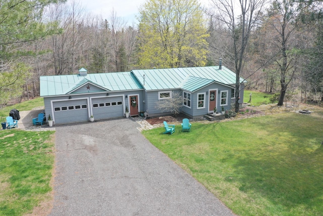 ranch-style home featuring a standing seam roof, metal roof, asphalt driveway, an attached garage, and a front yard