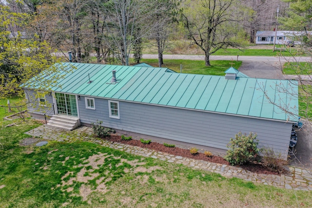 rear view of property with a standing seam roof, metal roof, and a lawn