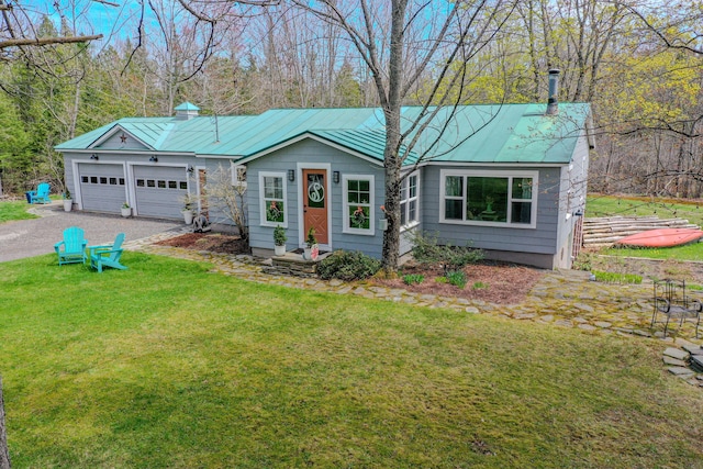 view of front of home with a chimney, driveway, a front lawn, and metal roof