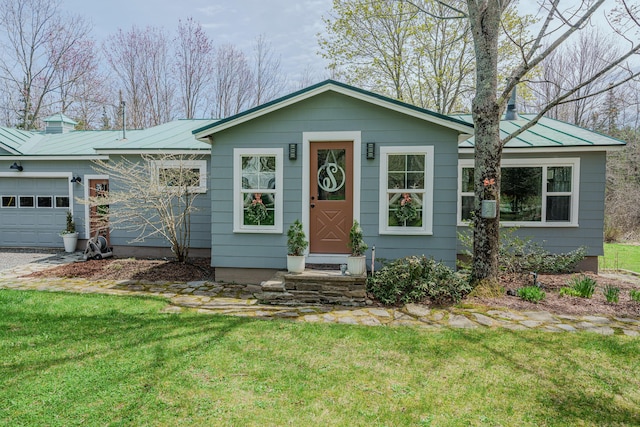 view of front of property featuring a garage, a front yard, metal roof, and a standing seam roof