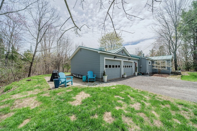 view of home's exterior with gravel driveway, a garage, metal roof, and a standing seam roof