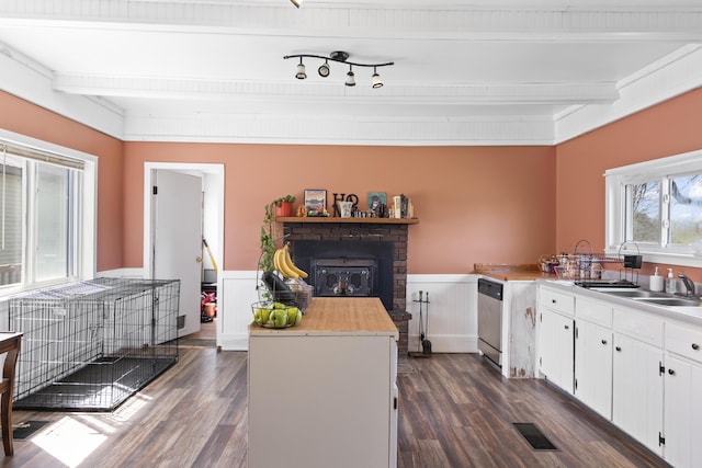1568 Hill Rd, Canaan, ME 04924 - kitchen with dark wood-type flooring, stainless steel dishwasher, a wainscoted wall, white cabinets, and beamed ceiling